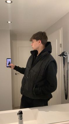 a young man is taking a selfie in front of the bathroom mirror with his cell phone