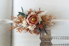 an open book with flowers and leaves on it next to a clock tower in the background