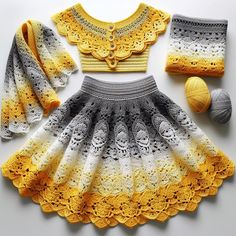 a crocheted dress, hat and scarf are arranged on a white surface next to balls of yarn