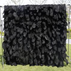 a large black furry rug sitting on top of a grass covered field next to a metal frame