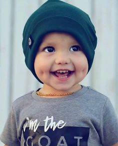 a young boy wearing a green beanie smiles at the camera