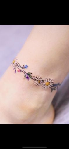 a woman's foot with flowers and leaves on the bottom part of her ankle