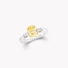 a yellow diamond ring with two baguettes on the sides and an inscription that reads grace