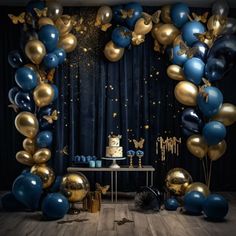 blue and gold balloons are on the wall in front of a table with a cake