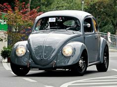 an old gray car driving down the street