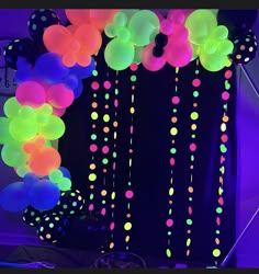 balloons and streamers hanging from the ceiling in front of a black backdrop with polka dots