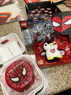 a spiderman cake in a box and some other toys