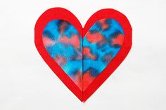 a paper heart cut in half with red and blue paint on it's side