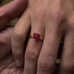 a man and woman's hands holding an engagement ring with a heart shaped ruby stone