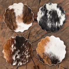 three cowhide coasters sitting on top of a wooden table