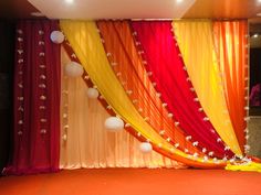 an orange, yellow and red backdrop with pom - poms on the side