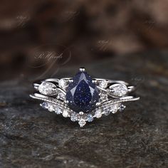 a blue diamond ring sitting on top of a black rock with white diamonds around it