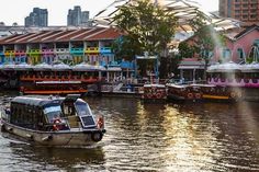 a boat is traveling down the river in front of some colorful buildings and water fountains