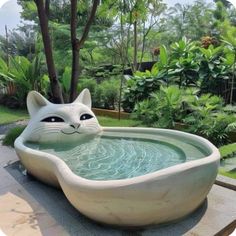 a cat shaped bathtub sitting on top of a table next to a lush green yard