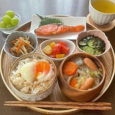 there are many different foods in bowls on the plate with chopsticks next to them