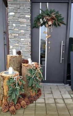 two logs with pine cones and evergreen leaves on them sitting in front of a door