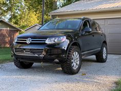 a black volkswagen suv parked in front of a house