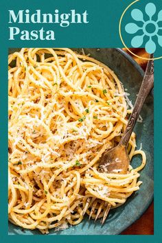 a plate of pasta with cheese and parmesan on the side, next to a spoon