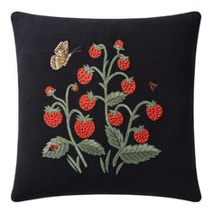 a black pillow with red berries and a butterfly on it