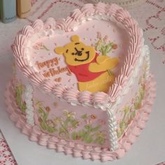 a winnie the pooh heart shaped cake with frosting on it's sides