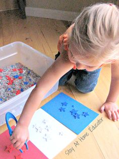 a young child is making snowflakes out of construction paper and glue on the floor