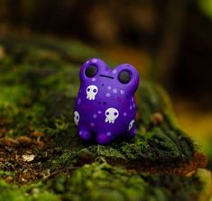 a purple frog toy sitting on top of green moss