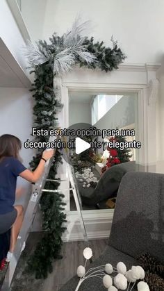 a woman standing on a ladder in front of a mirror next to a christmas tree