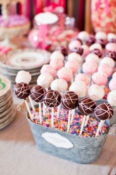 a table topped with lots of candy covered lollipops next to other desserts