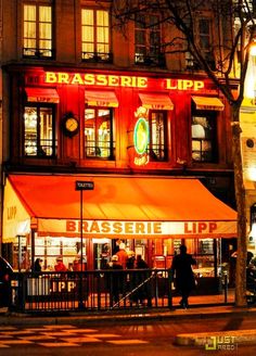 people are walking in front of a restaurant at night