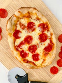 a pizza sitting on top of a cutting board next to a knife and pepperoni