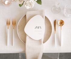 a place setting with white flowers and goldware on the table for an elegant wedding reception