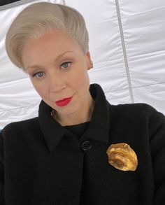 a woman with blonde hair wearing a black coat and holding an umbrella