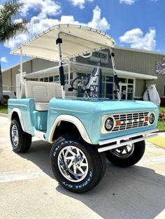 a light blue jeep with a white top parked in front of a building next to a palm tree