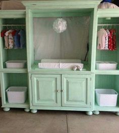 a baby crib with lots of clothes hanging on the top and bottom shelves in front of it