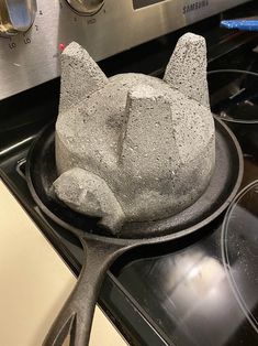 a cat shaped cake sitting on top of a black plate next to a stovetop oven