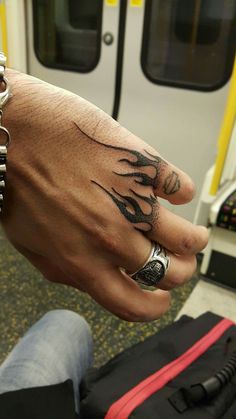 a person with tattoos on their fingers and hand next to a train door, holding onto a bag