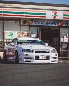 a white car is parked in front of a restaurant with japanese writing on the window