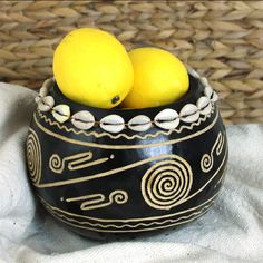 two lemons in a black bowl on a white cloth