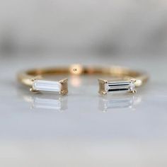 two gold rings with white stones on them