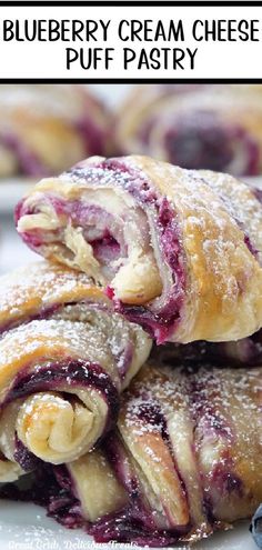 blueberry cream cheese puff pastry is stacked on top of each other with powdered sugar