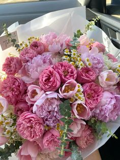 a bouquet of pink and white flowers sitting on top of a car dash boarder