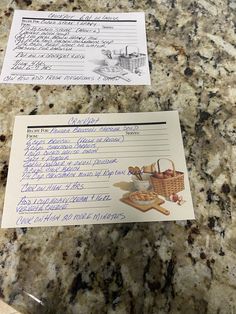 a note sitting on top of a counter next to a basket filled with bread and other items