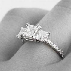 a woman's engagement ring with three princess cut diamonds on the band and side stones