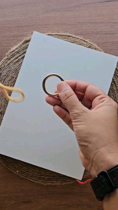 a person holding scissors over a piece of paper on a wooden table with twine