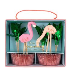 pink flamingo cupcakes in a box with green plants and palm trees on top