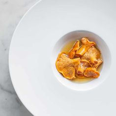 a white bowl filled with sliced mushrooms on top of a table