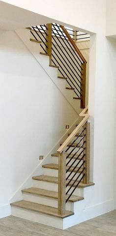 an empty room with a staircase and wooden handrail on the wall next to it