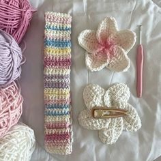 crocheted items are laid out on a white surface with yarn, scissors and knitting needles