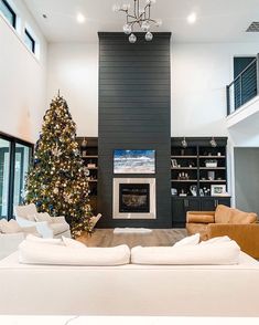 a living room filled with furniture and a christmas tree in front of a fire place