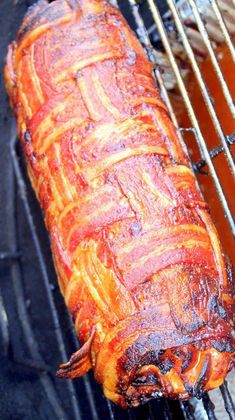 a large piece of meat is cooking on an outdoor bbq grill with tongs